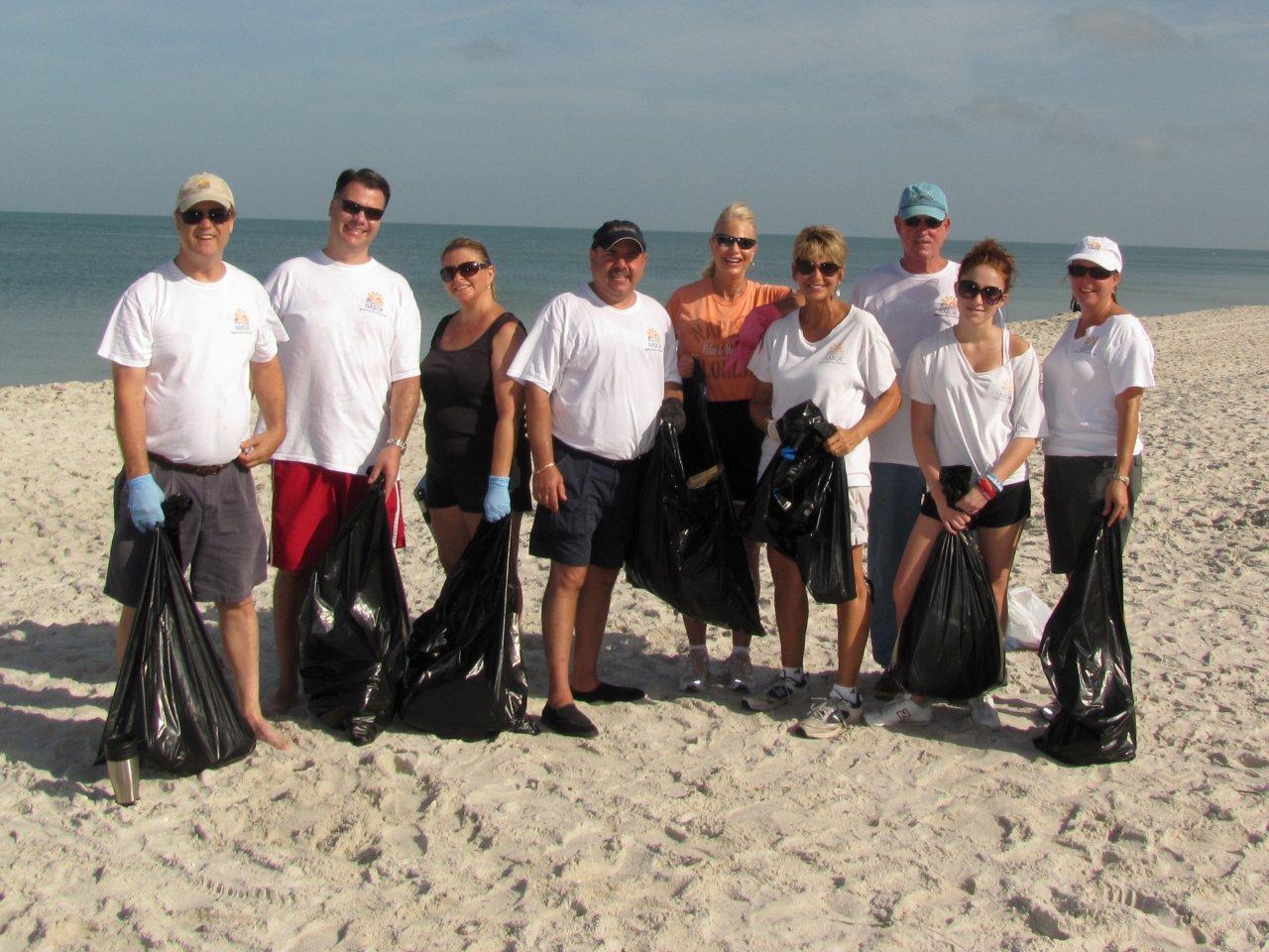 Members posing in front of trash collected during the annual beach cleanup at Naples Pier