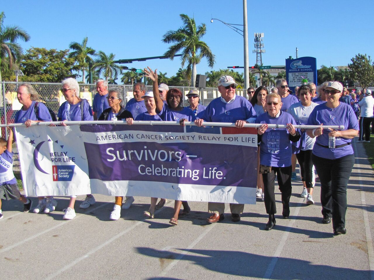 People participating in Relay for Life while holding a American Cancer Society banner